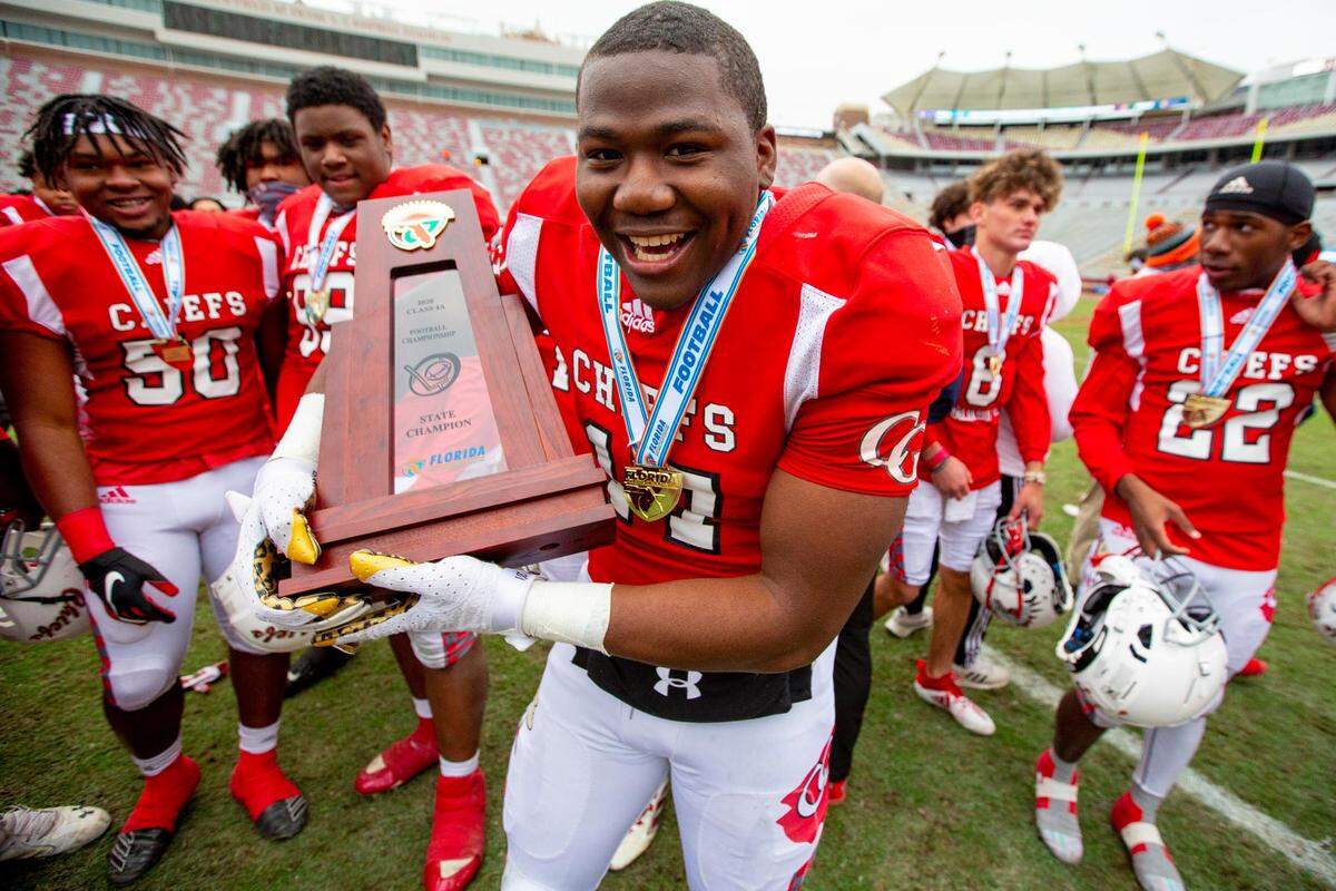 Cardinal Gibbons tightend Bryson Williams (17) cradles the Class 4A State Championship Trophy like a baby after defeating Jacksonville Bolles during the 4A State Championship at Doak Campbell Stadium in Tallahassee, Florida, on Thursday, December 17, 2020.