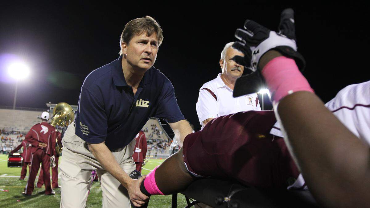 Dr. John Zvijac, orthopedic surgeon and sports medicine physician at Miami Orthopedics & Sports Medicine Institute, part of Baptist Health South Florida, examines a Miami Norland Senior High School football player at Nathaniel Traz-Powell Stadium by Miami Dade College’s North Campus .