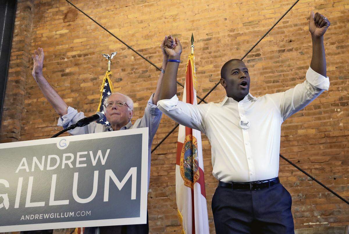 U.S. Sen. Bernie Sanders of Vermont, left, and Democratic gubernatorial hopeful Andrew Gillum hold hands during a campaign rally Friday, Aug. 17, 2018, in Tampa.