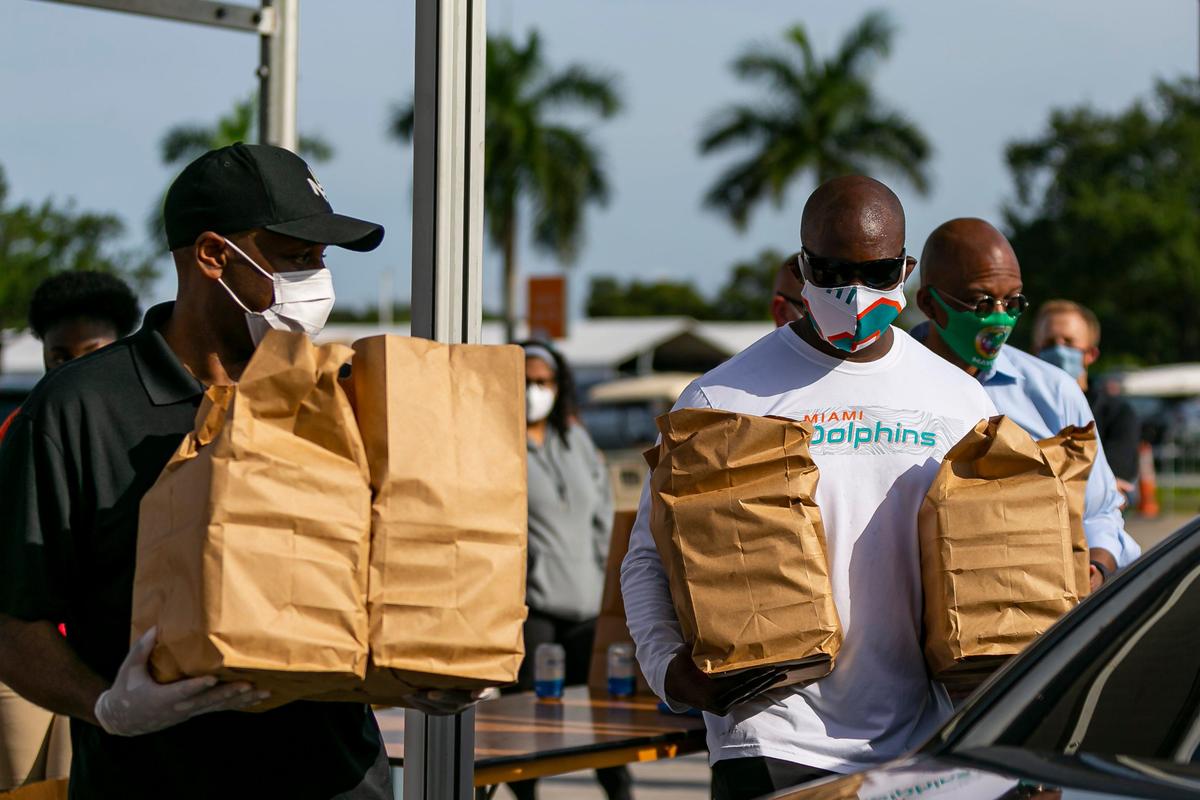 Miami Dolphins Chris Grier, left, and head coach Brian Flores, right, participate in a food drive event at the Hard Rock Stadium in Miami Gardens on Monday, June 1, 2020. The Miami Dolphins Foundation announced a multi-million-dollar commitment where they will provide a minimum of 1,000 meals each weekday up to a 12-month period to families in need in Miami Gardens through a voucher system.