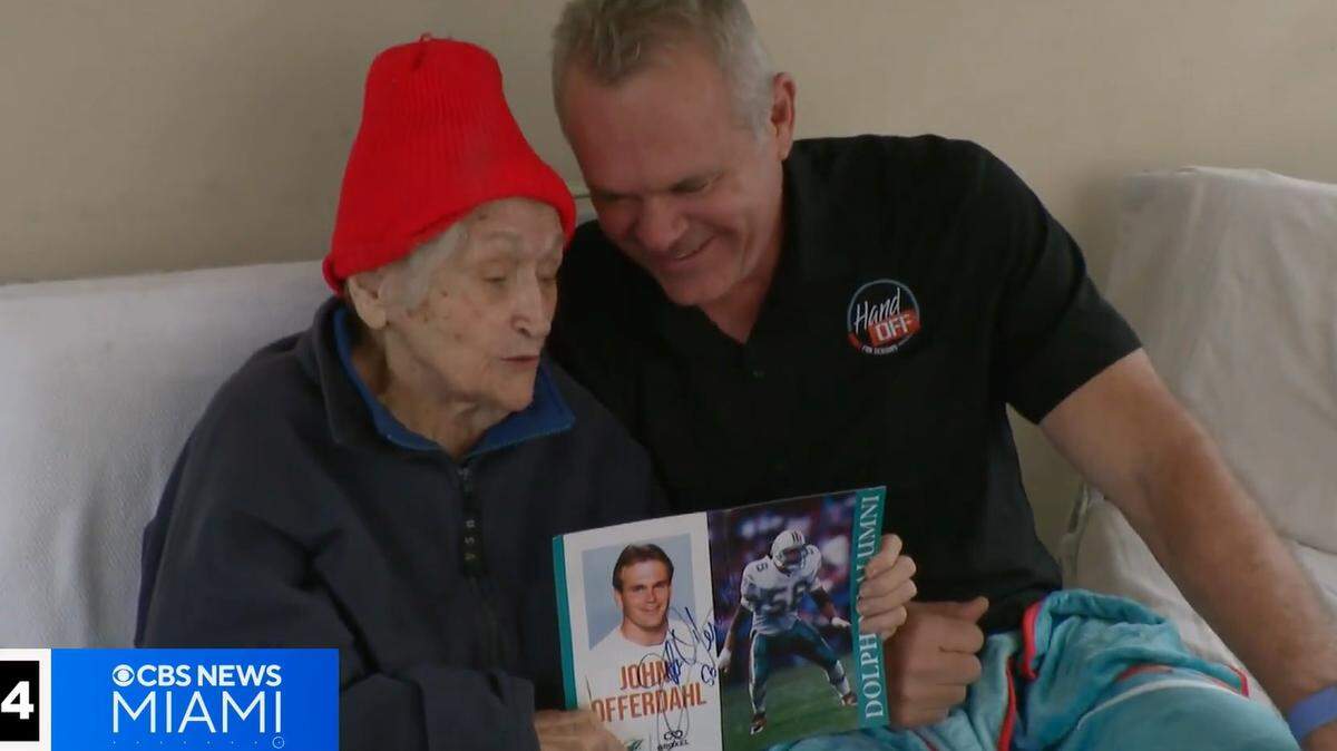 Barbara ‘BJ’ Mundy holds pictures of John Offerdahl during his days with the Miami Dolphins. Mundy is grateful for the meals that Offerdahl and volunteers deliver to her.