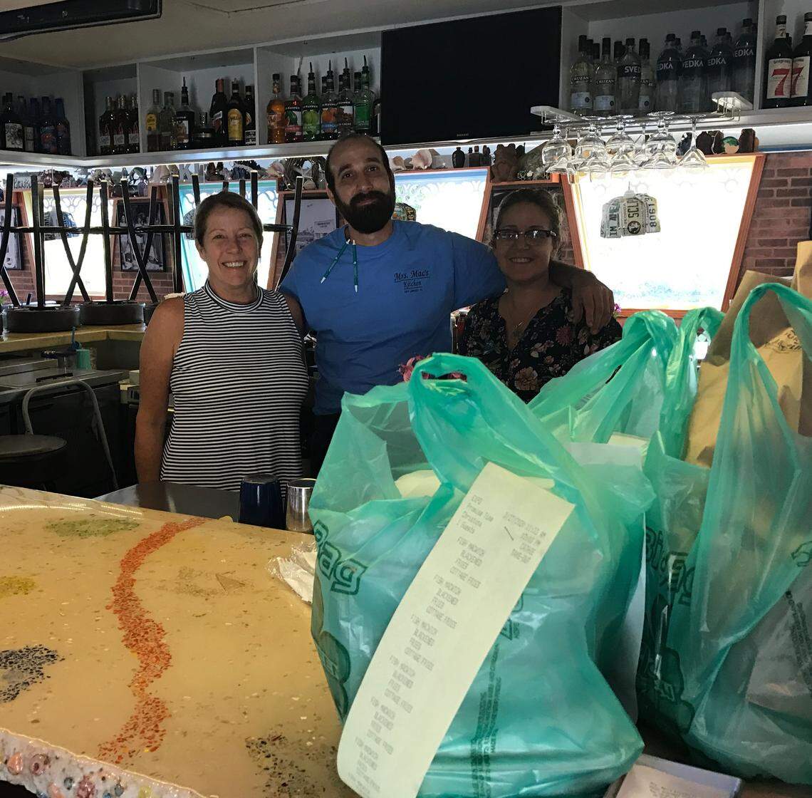 Nicolas Rodriguez, manager of Mrs. Mac’s Kitchen restaurant in Key Largo, is flanked by owners Angela and Paula Wittke behind a bar topped with takeout orders Friday, March 27, 2020.