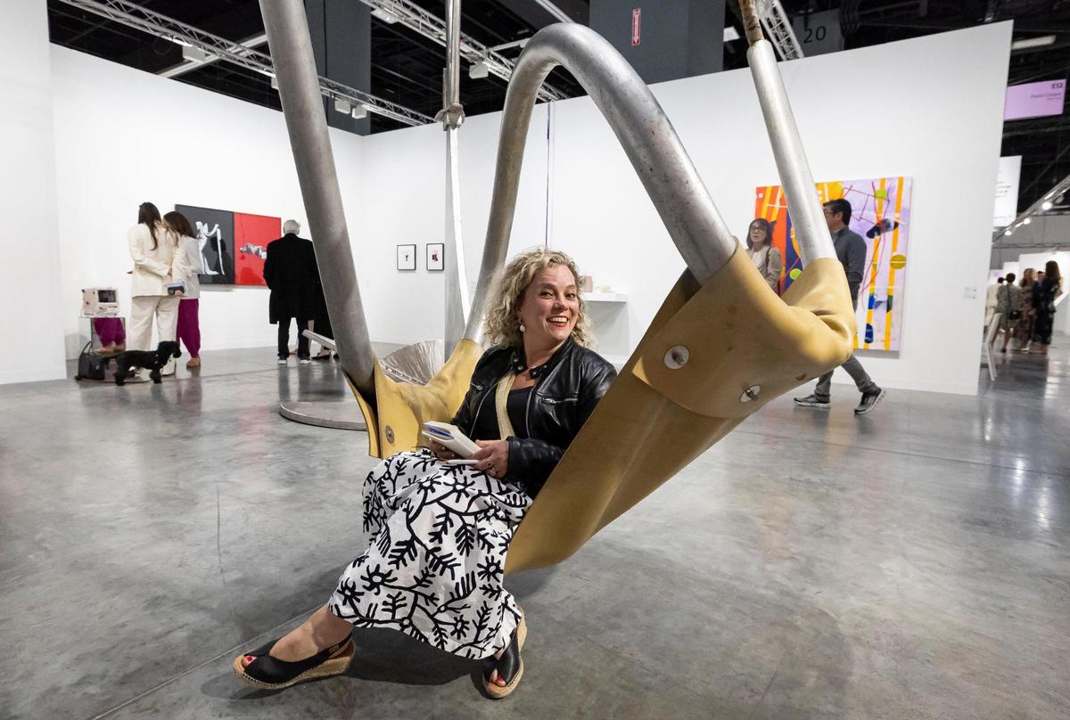 Katya Kazakina, from New York, sits on a swing by Mark Di Suvero, which was presented by Paula Cooper Gallery, during Art Basel at the Miami Beach Convention Center on Wednesday, Dec. 4, 2024, in Miami Beach, Fla.