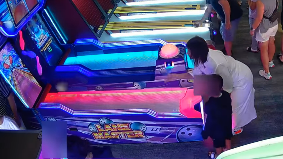 A woman is seen throwing an arcade game ball toward a group of people, police said.