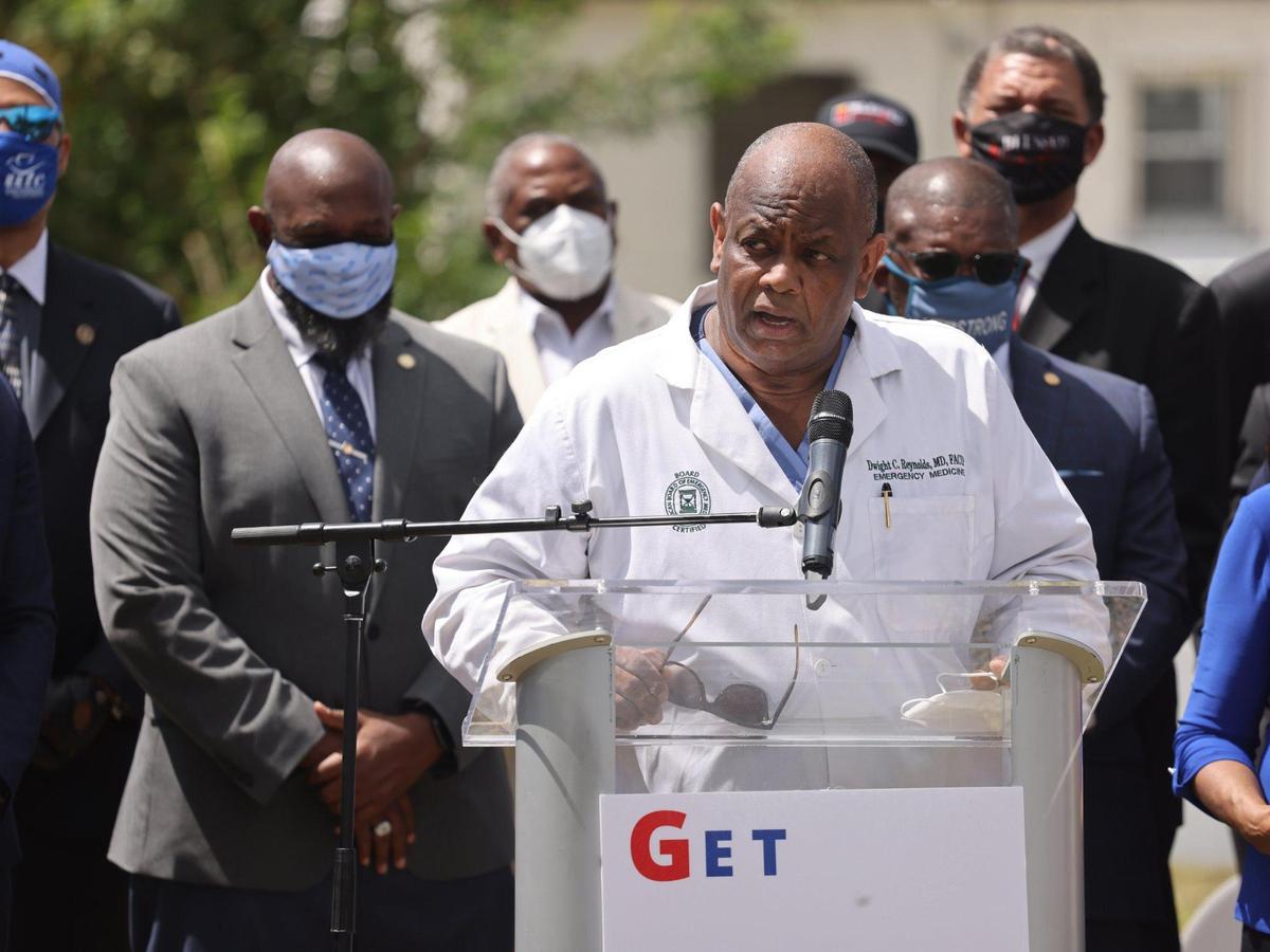 Dr. Dwight C. Reynolds, center, who is board certified in emergency medicine, urges members of the Black community to get vaccinated. On Tuesday, May 4, 2021 Congresswoman Frederica S. Wilson held a press conference to announce Get out the Vaccine Week in District 24 at the make-shift memorial cemetery at Simonhoff Park in Miami, Florida.