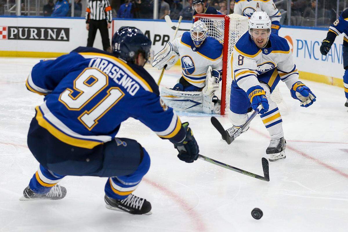 Buffalo Sabres’ Robert Hagg (8) and St. Louis Blues’ Vladimir Tarasenko (91) reach for the puck in front of Sabres goaltender Dustin Tokarski, center, during the second period of an NHL hockey game Friday, Feb. 25, 2022, in St. Louis. (AP Photo/Scott Kane)