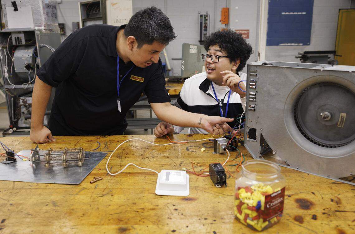 Gerald Flores, instructor in HVAC with the Electricity program and former student, left, helps a student with wiring during the day on Tuesday, Oct. 21, 2025, at Lindsey Hopkins Technical College in downtown Miami. 