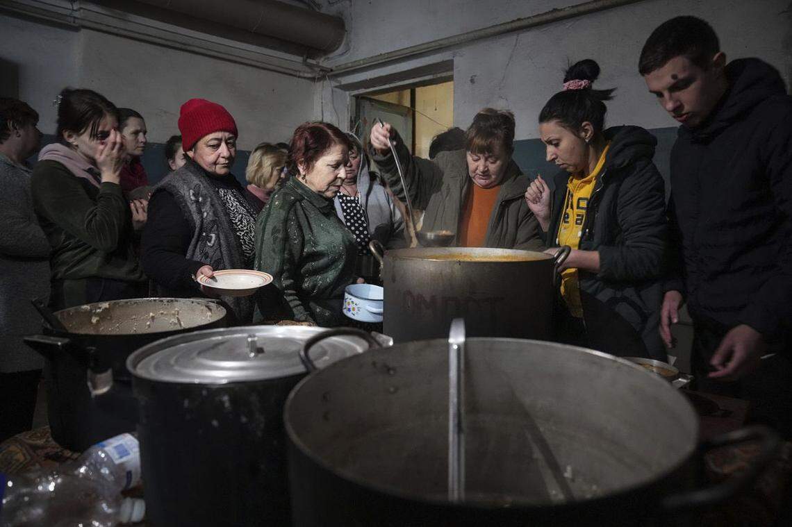 People line up to receive a hot meal in an improvised bomb shelter in Mariupol, Ukraine, in March.