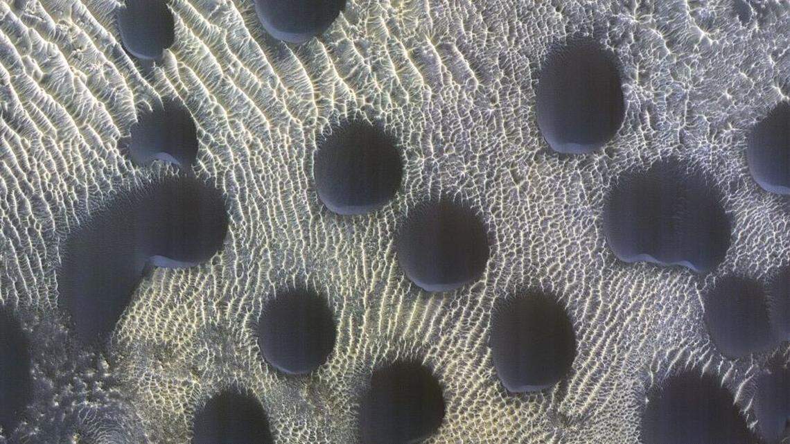 A probe orbiting Mars produces photos of “almost perfectly circular” sand dunes on the planet, mystifying researchers.