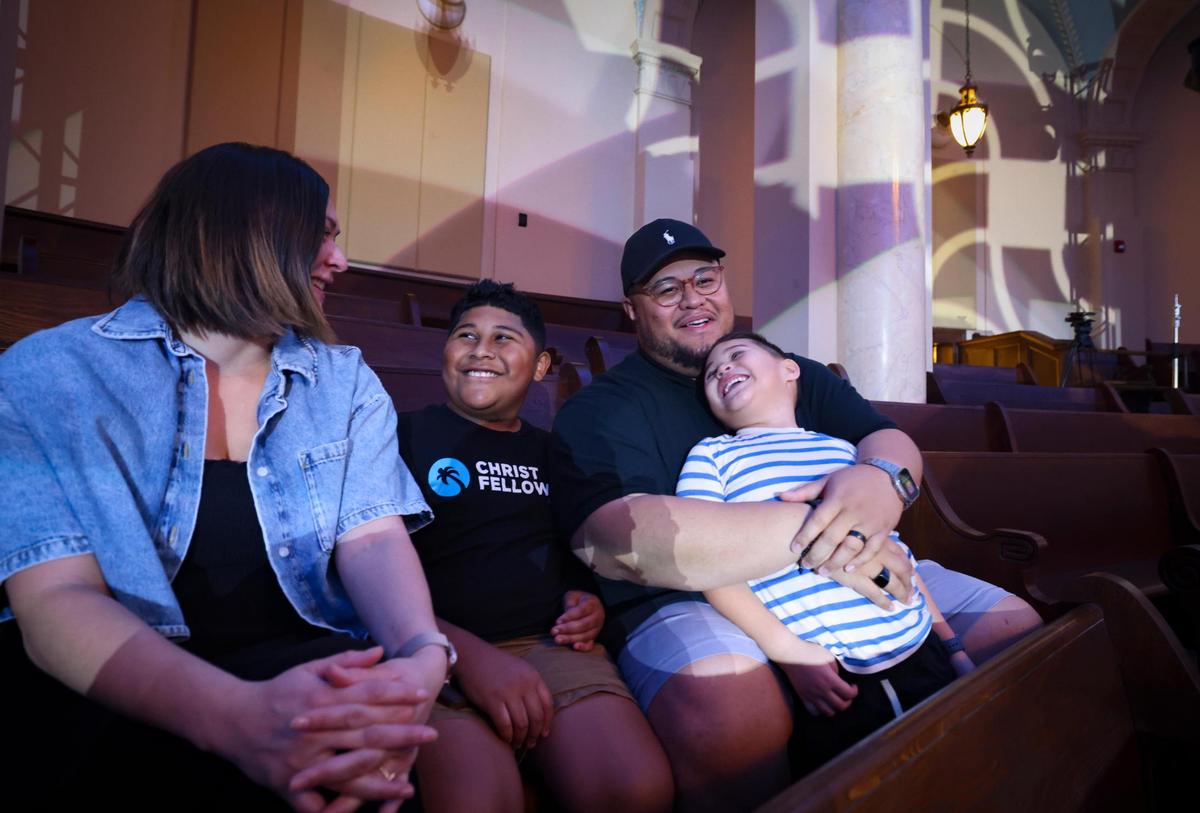 Christ Fellowship Pastor Gideon Apé sits in the balcony with his wife, Abby, left, and his sons, Jeremiah, 12, and Jude, 4. The family was at the historic church in downtown Miami during preparations for its grand re-opening.