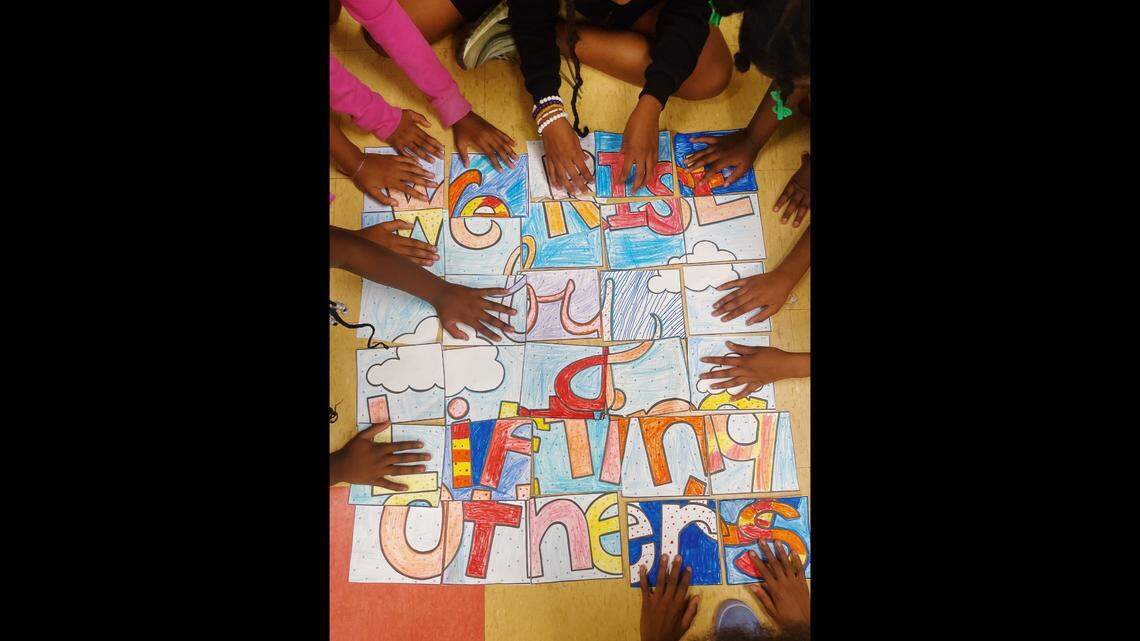 Girls from the Miami chapter of Girls Inc. put together a poster with a Robert Ingersoll quotation at Beacon College Prep in Opa-locka on Oct. 6, 2022. The full quotation is: ‘We rise by lifting others.’