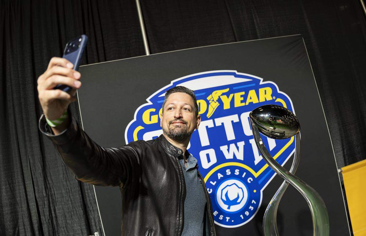 Rogelio Madan takes a selfie with the Cotton Bowl trophy at the Playoff Fan Central at the Miami Beach Convention Center on Friday, Jan. 16, 2025, in Miami Beach, Fla. Fans can visit the event ahead of the College Football Playoff National Championship Game between the Miami Hurricanes and the Indiana Hoosiers and enjoy a variety of family-friendly interactive experiences.