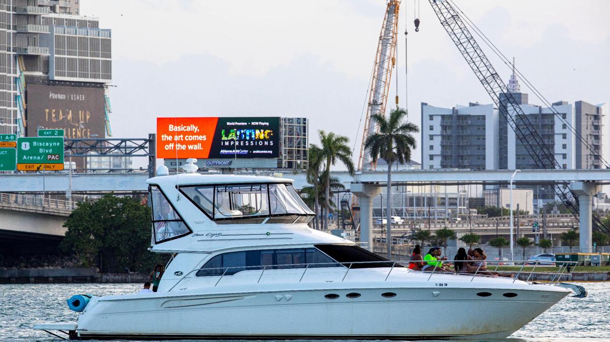 A giant new electronic billboard flashes on the former 1 Herald Plaza property in the background as a boat cruises by with people enjoying Biscayne Bay in Miami, Florida, on Tuesday, June 22, 2021.