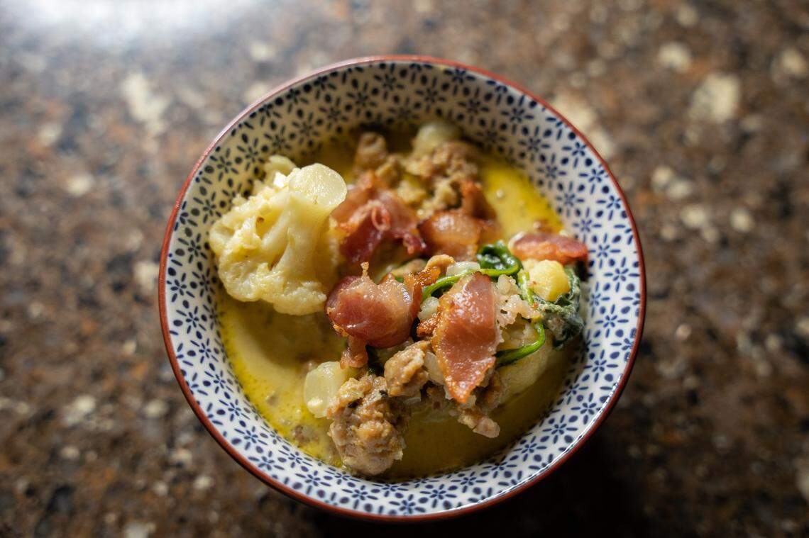 A bowl of Zuppa Toscana from the top, garnsihed with bacon and cauliflower.