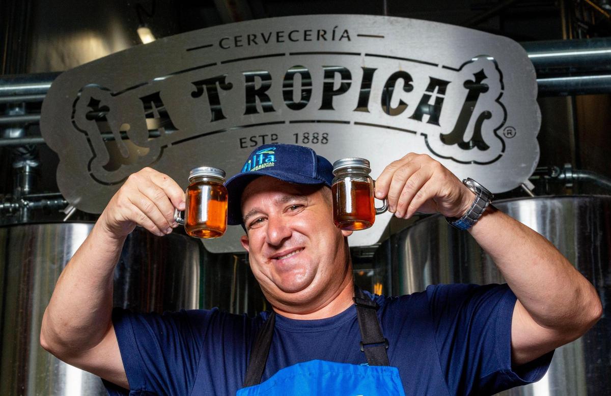 Filta service technician Richard Erin holds up two glass jars with the filtered cooking oil, left, and unfiltered oil, right, after using the mobile filtration unit at Cerveceria La Tropical in the Wynwood neighborhood of Miami, on Wednesday, May 24, 2023.
