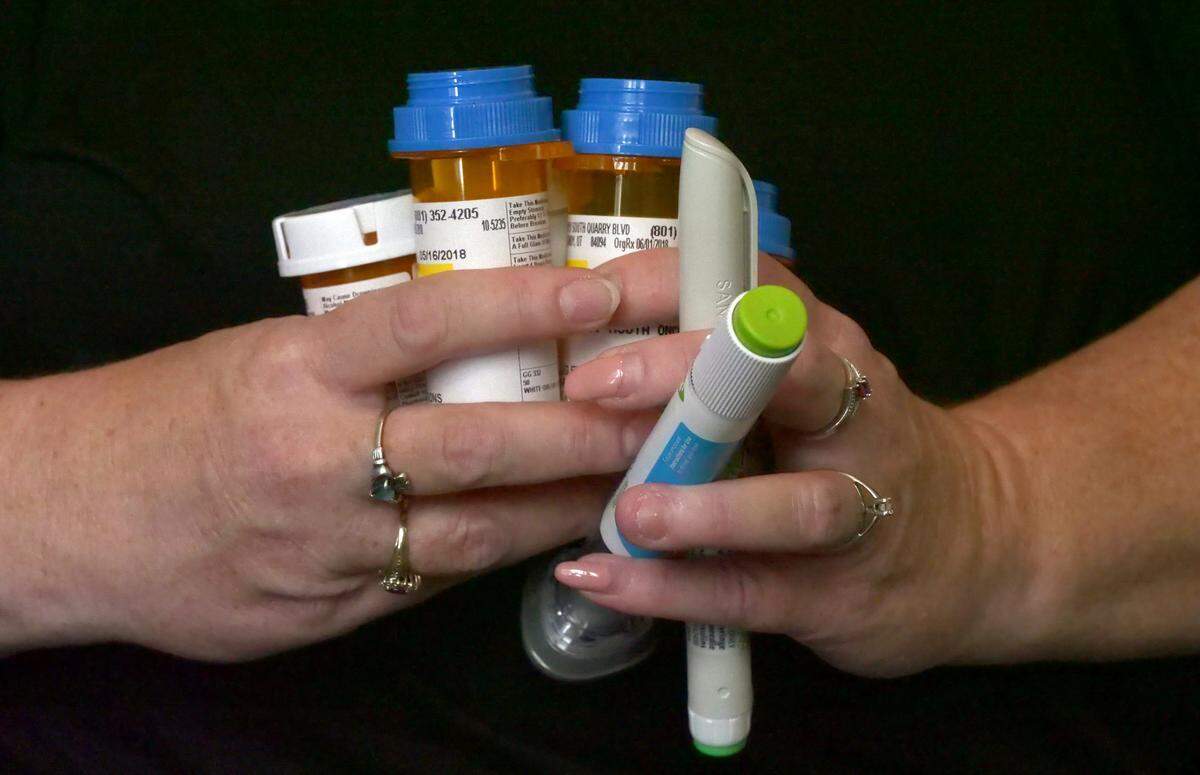 In this July 11, 2018, photo, Bridgett Snelten holds her prescriptions as she sits in her home, in Sandy, Utah. Snelten has diabetes and has had to change health insurance plans three years in a row. Twice, new insurers wouldn’t cover Trulicity, a once-a-week injected diabetes medicine she’d been taking that helped control her blood sugar tightly. Instead, they made her return to an inexpensive, twice-a-day injected diabetes drug she and her doctor knew didn’t work for her.