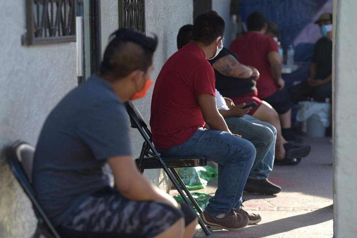 People sit six feet apart waiting their turn to register for a free COVID-19 test during a Doctors Without Borders (Médecins Sans Frontières) health clinic on Thursday, June 11, 2020, in Immokalee. The international humanitarian medical group launched its first mission in Florida in May to provide testing, public health education and tele-health consultations for farmworkers, who are considered at high risk for COVID-19 due to their working and living conditions.