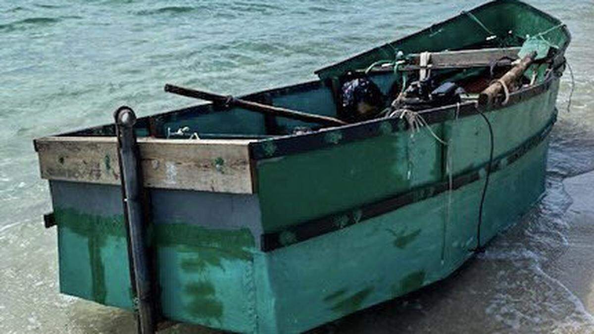 A small, green row boat sits on the sand on Miami Beach Friday, April 29, 2022. The Border Patrol says the vessel is a migrant boat that carried six people to South Florida.
