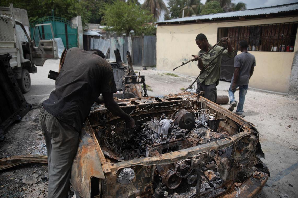 Men salvage parts from a charred car that was set on fire during clashes between armed gangs in the Butte Boyer neighborhood of Port-au-Prince, Haiti, Friday, May 13, 2022. Dozens of people, including women and children, have been killed in recent weeks amid new clashes between gangs fighting over territory as their power grows following the July 7, 2021, assassination of President Jovenel Moïse.