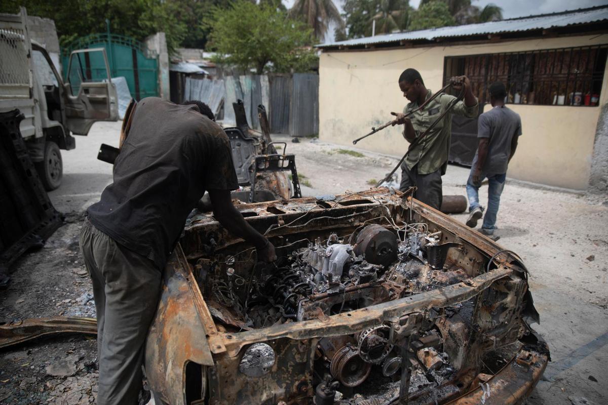 Unos hombres rescatan partes de un coche carbonizado que fue incendiado durante enfrentamientos entre pandillas armadas en el barrio de Butte Boyer de Puerto Príncipe, Haití, el viernes 13 de mayo de 2022. Decenas de personas, entre ellas mujeres y niños, han muerto en las últimas semanas en medio de nuevos enfrentamientos entre pandillas que luchan por el territorio a medida que aumenta su poder tras el asesinato del presidente Jovenel Moïse el 7 de julio.