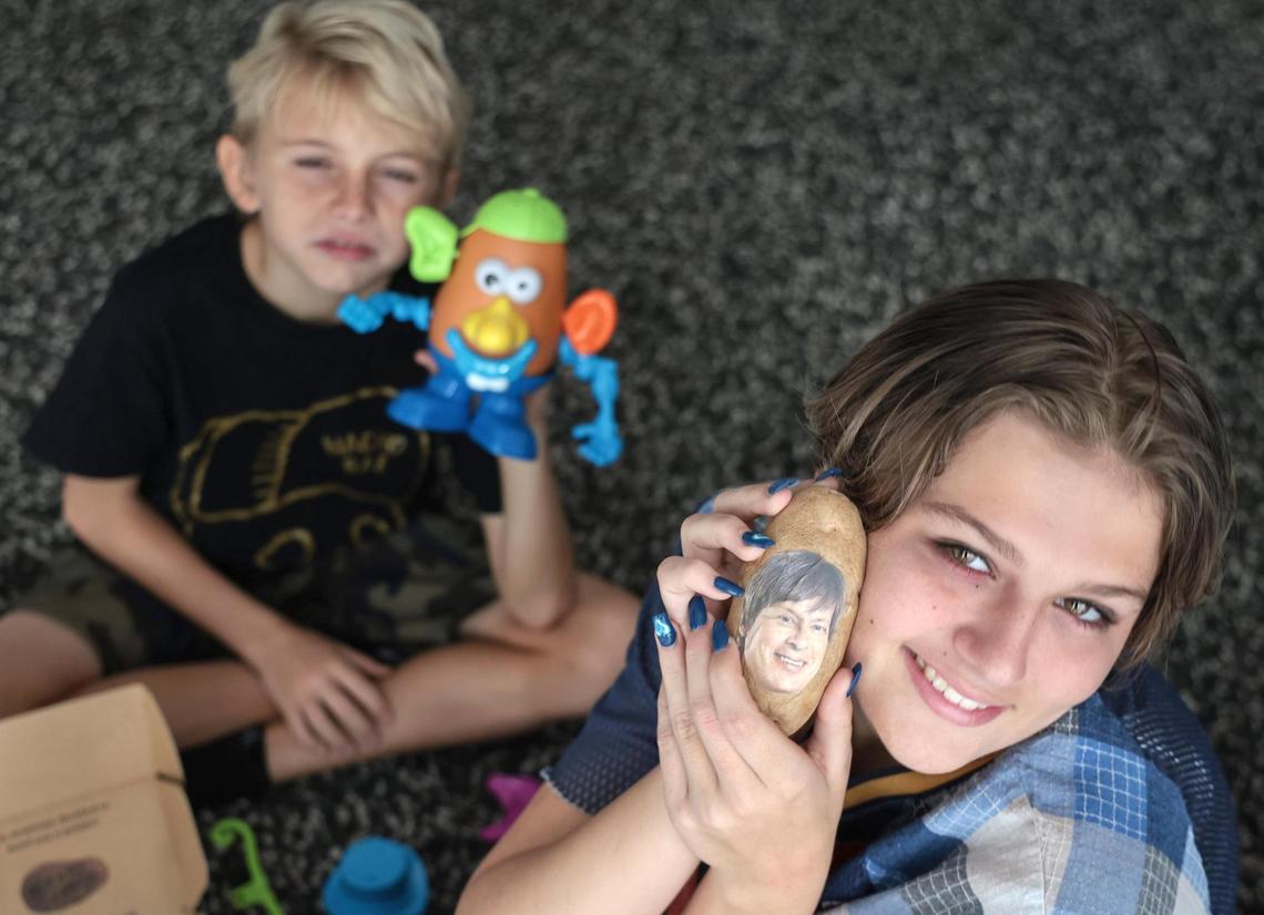 Pax Griffin, 10, left, cannot compete with his sister Madelaine ‘Madge’ Griffin, 13, as she adores her Potato Parcel with Dave Barry’s face planted on the potato. Location: At the home of Carl Juste.