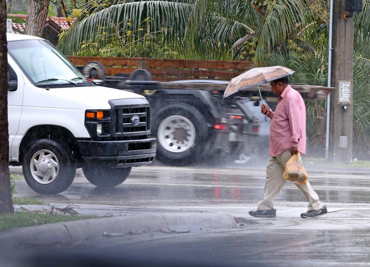 A man walks along SW 15th Ave. in Fort Lauderdale in the rain, February 7, 2020. Early morning storms snarled traffic in South Florida.