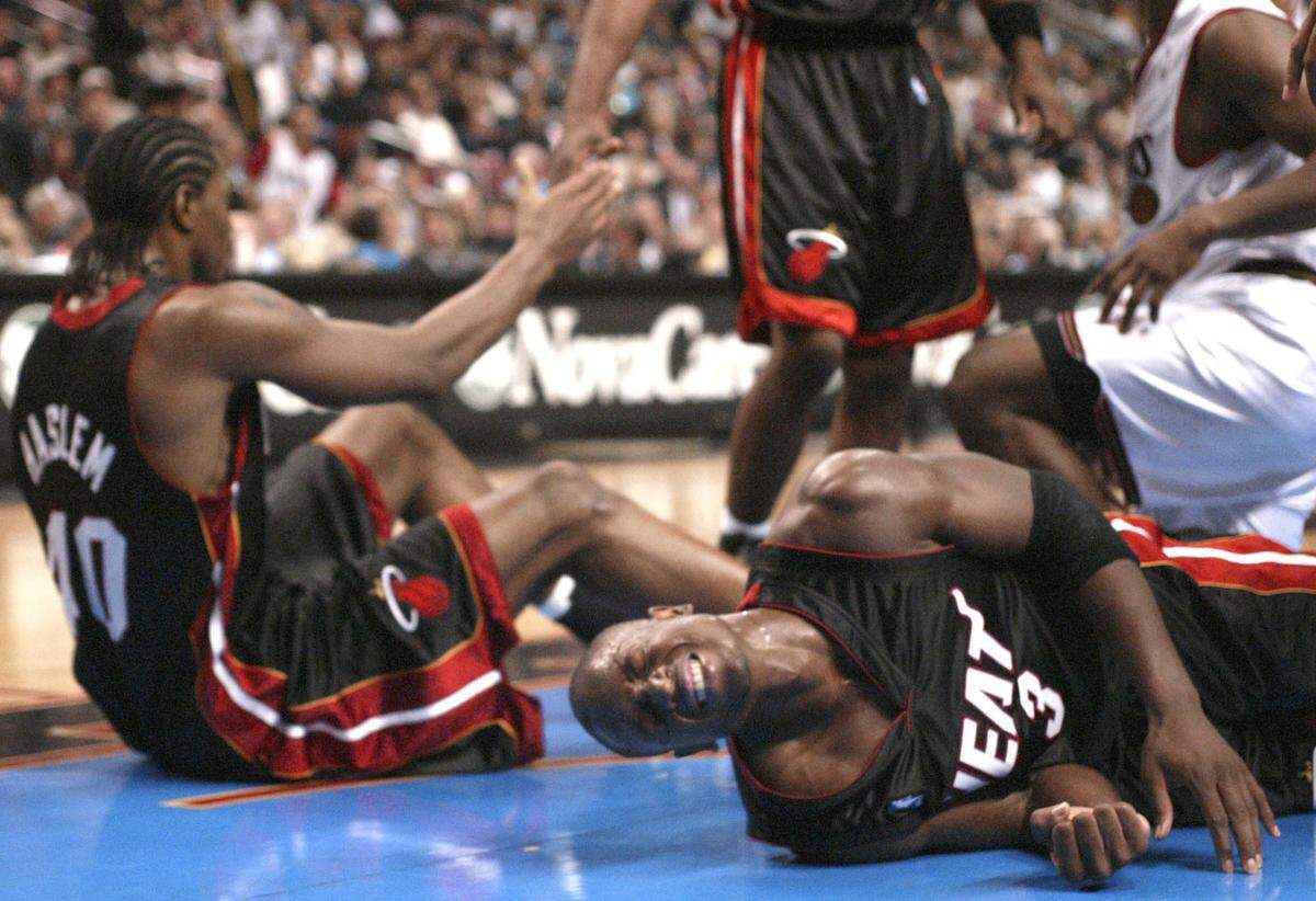 Miami Heat’s Dwyane Wade (3) grimaces and teammate Udonis Haslem (40) gets a hand after a pileup in the paint against the Philadelphia 76ers in the first half Tuesday, Oct. 28, 2003, in Philadelphia. Wade led the Heat with 18 points, but the 76ers won, 89-74. The game marked the NBA Debuts for Wade and Haslem.
