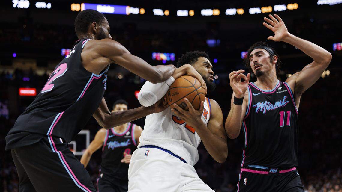 Miami Heat forward Andrew Wiggins (22) tries to get the ball from New York Knicks center Karl-Anthony Towns (32) while Miami Heat forward Jaime Jaquez Jr. (11) guards during the second half of a game on Nov. 17, 2025, at Kaseya Center in Miami.