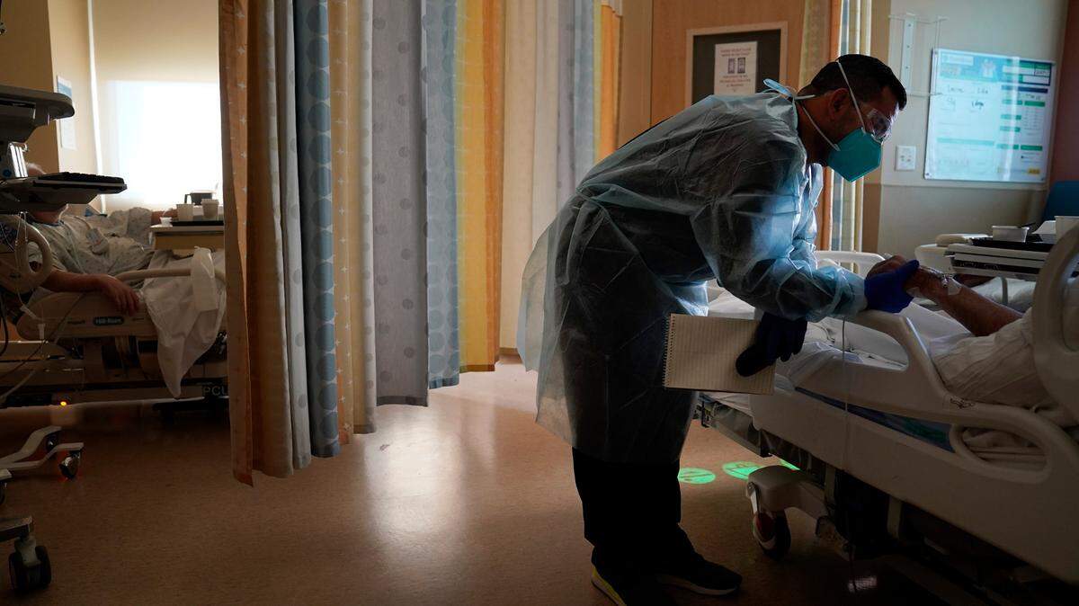 In this photo, chaplain Elias Mena holds the hand of a COVID-19 patient while praying for him at Providence Holy Cross Medical Center in the Mission Hills section of Los Angeles on Friday, Jan. 15, 2021.