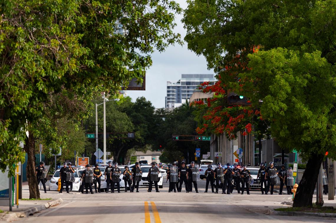 Police officers keep guard near their headquarters as activists march toward Overtown during a ‘Justice for George Floyd’ protest in downtown Miami on Monday, June 1, 2020.