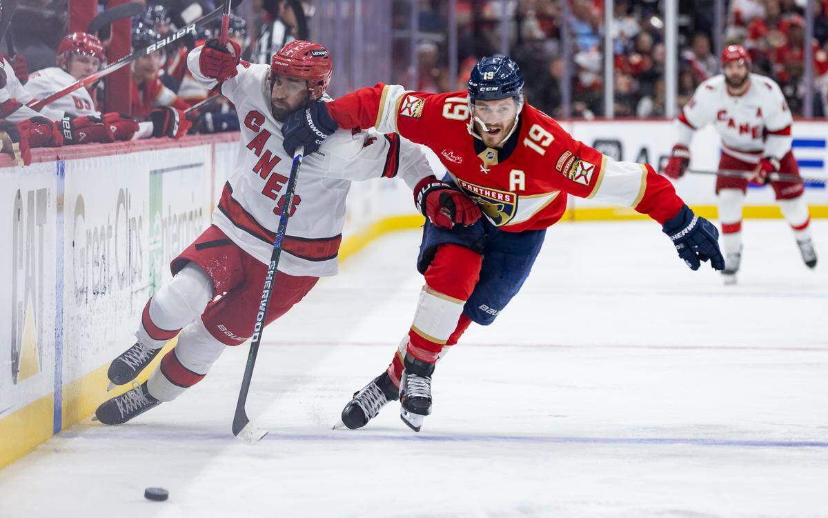 Florida Panthers left wing Matthew Tkachuk (19) and Carolina Hurricanes defenseman Shayne Gostisbehere (4) compete for the puck in the third period of Game 4 during the Eastern Conference final of the NHL Stanley Cup playoffs at Amerant Bank Arena on Monday, May 26, 2025, in Sunrise, Fla.