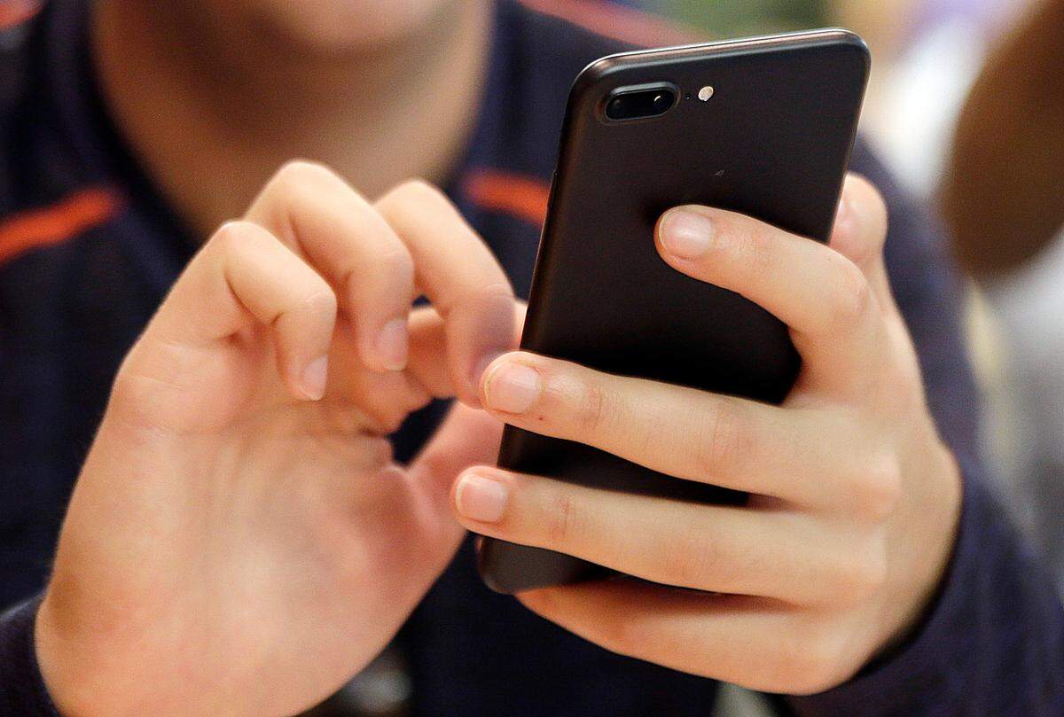FILE - In this Sept. 16, 2017, file photo, a person uses a smart phone in Chicago. For many of us, a smartphone addiction is not so much a debilitating disease but a constant, nagging inconvenience we can’t seem to shake. But it’s not all our fault. From the constant notifications to the color schemes to the “likes,” followers and in-game rewards out phones and the apps on them were created so we’ll use them as much as possible. But there are ways to fight back. (AP Photo, File)
