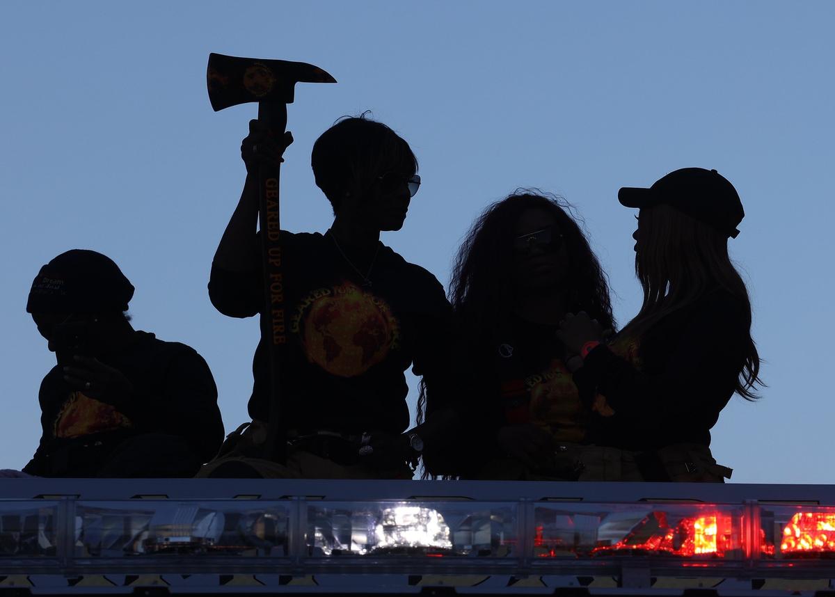 Women of color of Miami-Dade Fire Rescue stand on top of a fire truck, their silhouettes cast against the sky, during a parade honoring Martin Luther King Jr. in Liberty City Monday.