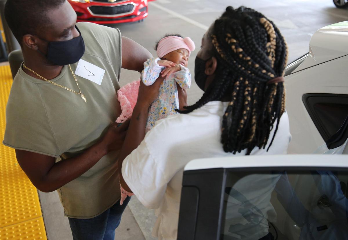 Jean Costume hands baby Remy to his wife Alena as they prepare to leave Memorial Hospital West in Pembroke Pines on May 19, 2020.