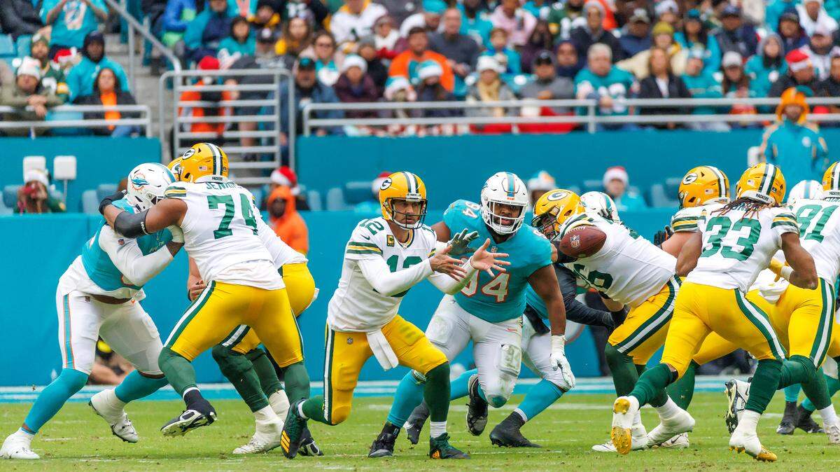 Green Bay Packers quarterback Aaron Rodgers (12) toss the football to Packers running back Aaron Jones (33) during third quarter of an NFL football game against the Miami Dolphins at Hard Rock Stadium on Sunday, December 25, 2022 in Miami Gardens, Florida.