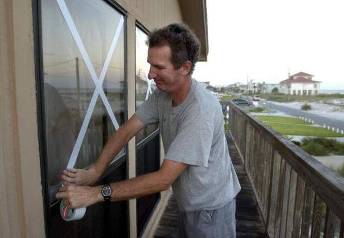 A Pensacola Beach resident taped windows in advance of Hurricane Ivan in 2004. At the time a Florida PACE program gave homeowners money to better secure their homes, installing storm-impact windows, for example. Taping windows does not protect them from hurricane-force winds.