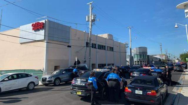 The top of the white Mercedes SUV can be seen on the left crashed into a power pole and the side of Office Depot. Miami Beach police say a man tried to steal the car from the car wash across the street.
