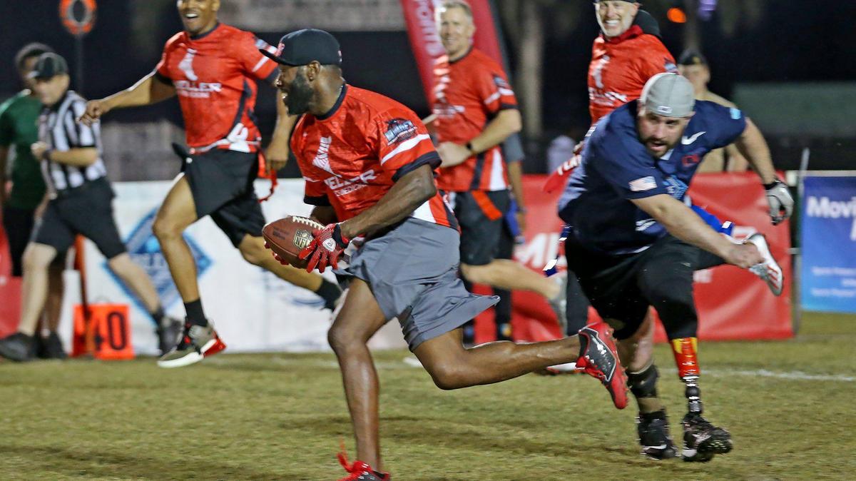 Dynamic Warrior chases WWAFT and NFL alumni Denver Bronco Nick Ferguson runs with the ball in a Wounded Warrior Project football game at Nova HS in Davie, Florida, January 30, 2020.
