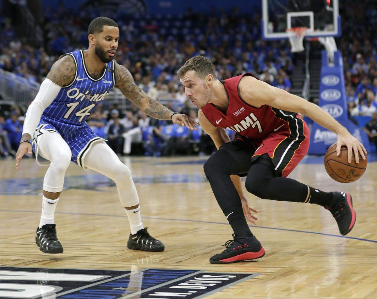 El armador del Heat Goran Dragic (der.) busca dar un pase ante el marcaje del jugador del  Magic D.J. Augustin, en el juego inaugural este 17 de octubre en Orlando.