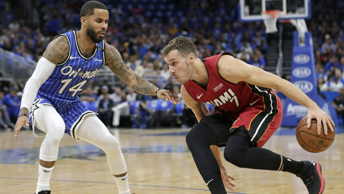 El armador del Heat Goran Dragic (der.) busca dar un pase ante el marcaje del jugador del  Magic D.J. Augustin, en el juego inaugural este 17 de octubre en Orlando.