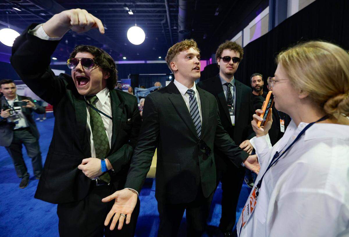 Eugene Kacherov and John Colton join others as they heckle CNN reporter Elle Reeve in the exhibition area during the Turning Point Action Conference at the Palm Beach County Convention Center in West Palm Beach, Florida, on Saturday, July 15, 2023.