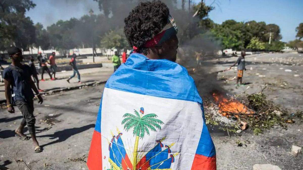 A demonstrator stands draped in the Haitian flag in Port-au-Prince during a protest against Haiti’s President Jovenel Moise.