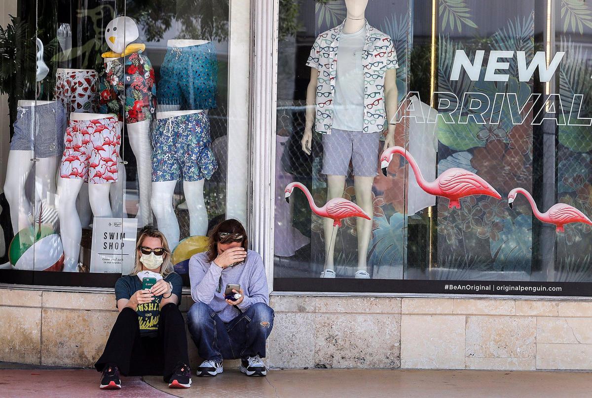 As Lincoln Road Mall businesses begin to reopen, visitors take a moment to check their phones.