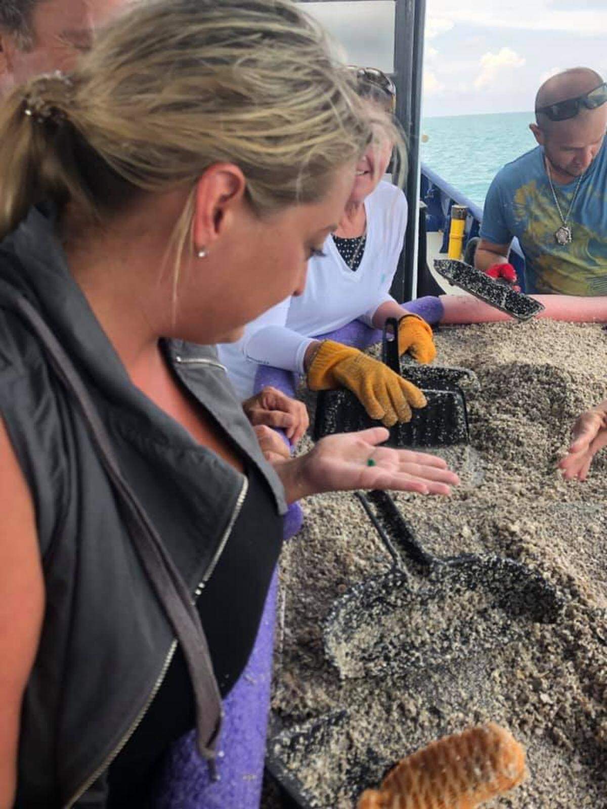 Employees of Mel Fisher’s Treasures search for treasure by sifting through sand taken off the ocean floor.