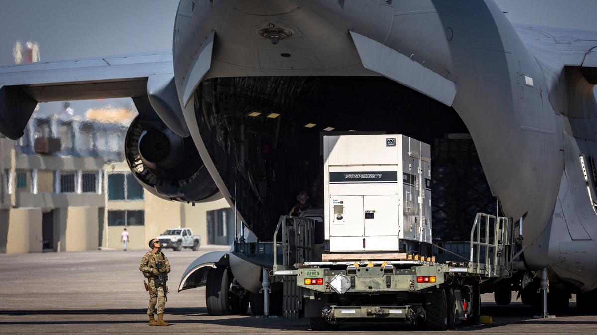 A United States serviceman stands guard on Wednesday, May 15, 2024, as supplies are unloaded from a U.S. Air Force C-17 cargo plane on the tarmac at Toussaint Louverture International Airport in Port-au-Prince, Haiti. The plane was carrying supplies for the camp being built for Kenyan police officers who will lead a Multinational Security Support mission into Haiti.