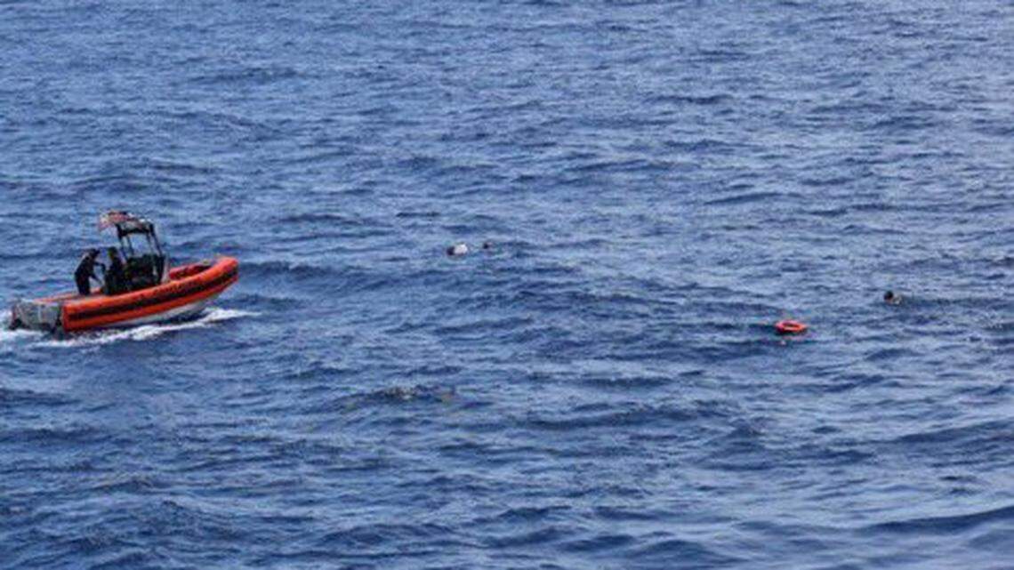 A U.S. Coast Guard patrol boat approaches people in the water about 16 miles south of Key West Thursday, May 27, 2021. Two people died when a boat flipped over the night before. The Coast Guard rescued eight people, but 10 people remained missing. The people are Cubans who were attempting to migrate to the United States.