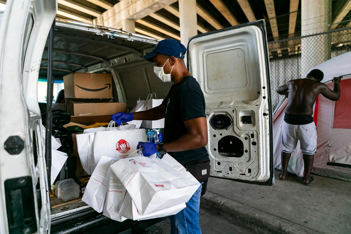 Armen Henderson, a University of Miami internist, works with a group of community volunteers to provide COVID-19 tests to the homeless in Miami’s Overtown neighborhood on Friday, March 27, 2020. Henderson also provided food and hand sanitizers.