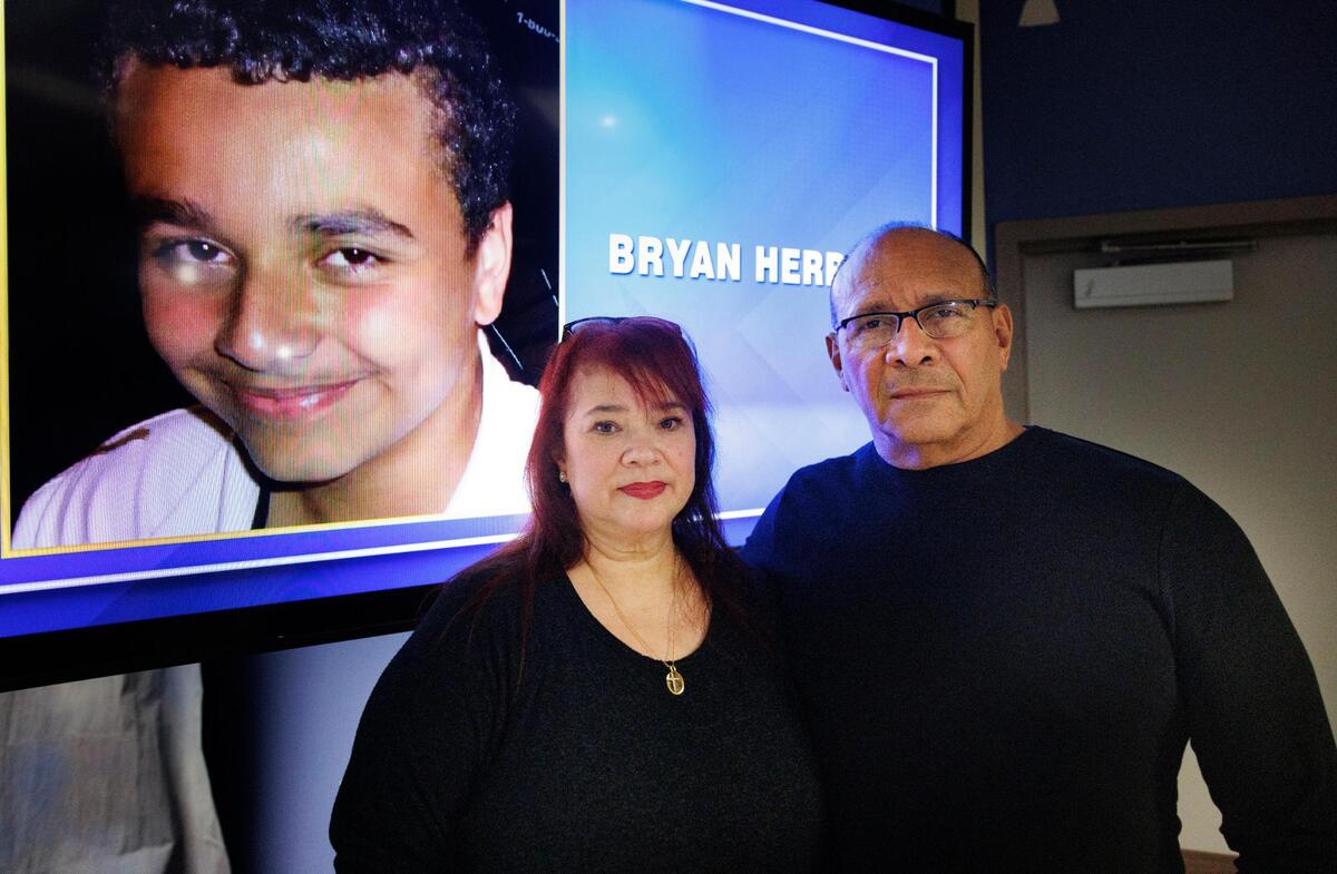 Anabel and William Herrera pose next to a photo of their late son Bryan. He was 16 years old when he was shot and killed while riding his bicycle before Christmas in 2012.
