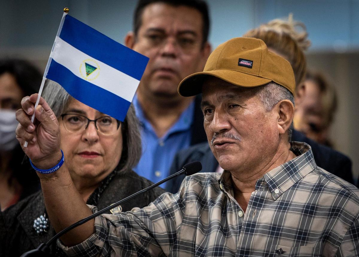Miami, FL- February 15, 2023 - Former Nicaraguan Political prisoners Victor Manuel Sosa Herrera, right, raises the Nicaraguan flag with the inverted national seal in the center as a sign of protest, as he speaks to reporters during a press conference at the Stephen P. Clark Government Center in downtown Miami. Miami-Dade County Mayor Daniella Levine Cava met with recently released political prisoners from Ortega’s regime in Nicaragua. She offered assistance and support to them and their families.