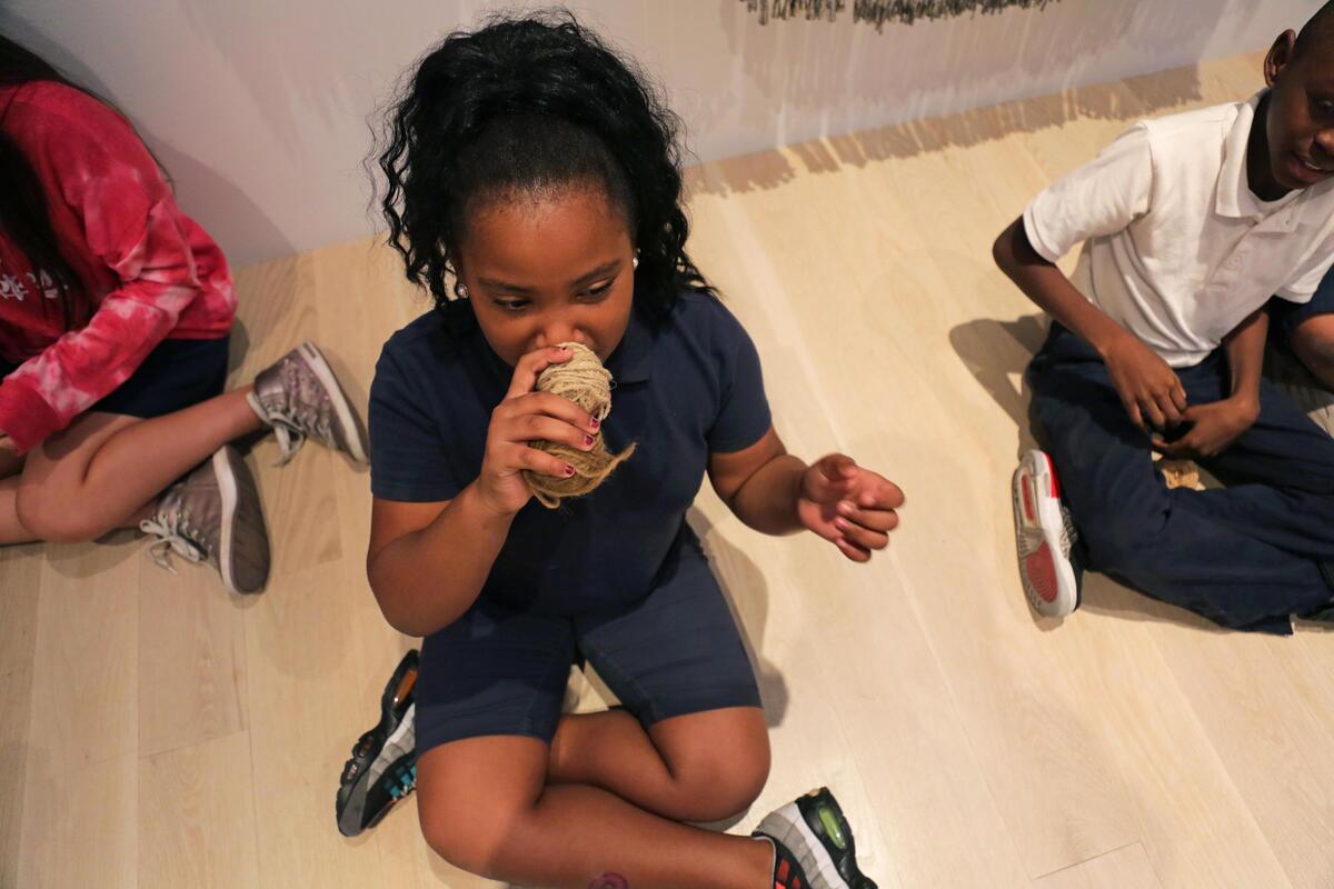 Victoria Gaines, 9, a fourth-grader at Toussaint L’Ouverture Elementary School, smells a thread used for weaving by Navajo artist Eric-Paul Riege during a school visit to the Institute of Contemporary Art Miami on Tuesday, October 1, 2019.